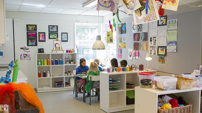 Fyra barn som sitter vid ett bord och målar i en kreativ miljö på förskolan